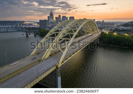 Daniel Carter Bridge in Cincinnati city, Ohio, USA with highway traffic driving cars in downtown district. American city skyline with brightly illuminated high commercial buildings at sunset