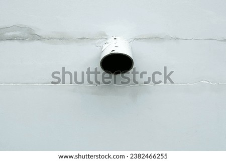 A plastic pipe hole on the white wall of the building for texture and backgrounds.