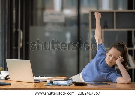 Businesswoman stretching lazy at the desk to relax while working in the office. Feeling stressed and achy from work.
