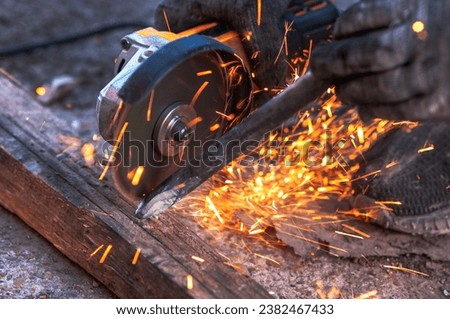An angle grinder in the hands of a worker sharpens a steel impact tool for a jackhammer. Sparks fly from the power tool blade. Selective focus.