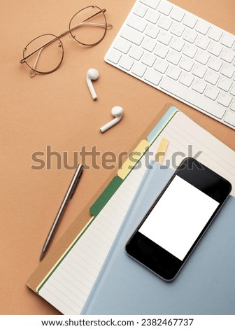 Top view  of office  supplies, smartphone with blank mockup screen, over notebooks,  pens, glasses