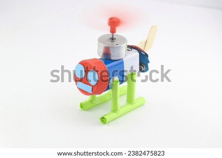 Toy helicopter built at home using battery and dc motor and other recycled parts on a white background