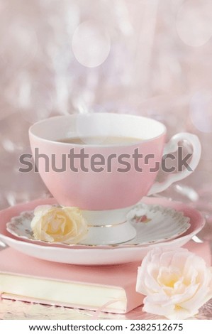Pink mug book and flowers on a blurred background with spots of light and rays. Soft focus. Vertical image. greeting card