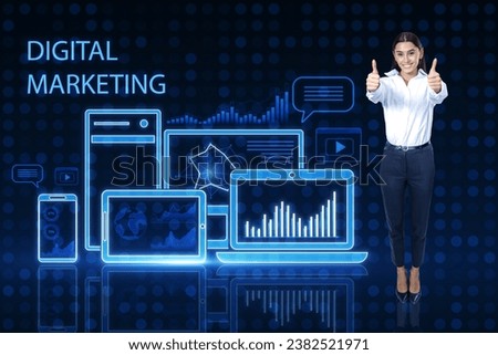 Attractive young european businesswoman showing thumbs up on blue pixel background with gadgets and business chart hologram. Digital marketing, finance, social network and online service concept