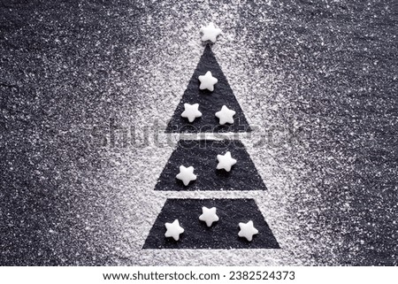 Christmas tree made of flour on black background, sugar stars, creative christmas background 