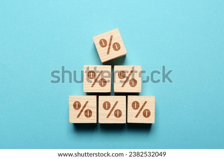 Wooden cubes with percent signs on light blue background, top view