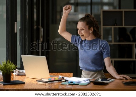 Happy business woman celebrating victory while receiving good news on her laptop, excited about success.