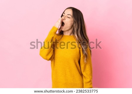 Young Romanian woman isolated on pink background yawning and covering wide open mouth with hand Royalty-Free Stock Photo #2382533775