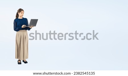 Asian woman wearing casual wear using a laptop PC. Wide angle visual for banners or advertisements.