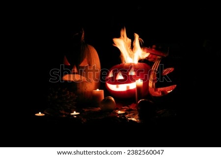 Halloween pumpkin fire smile and scary eyes for party night. Close up view of scary Halloween pumpkin with fire eyes at black background. Soft focus. Blurred background