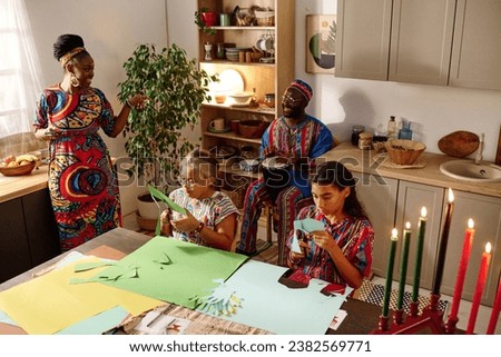 Two girls cutting paper and preparing greeting cards for kwanzaa holiday