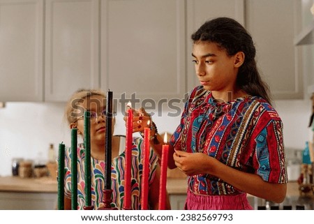 Cute African American girl in national attire burning candles for kwanzaa