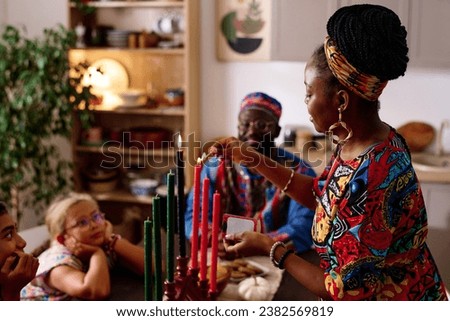 Side view of young woman burning candles symbolizing kwanzaa principles Royalty-Free Stock Photo #2382569819