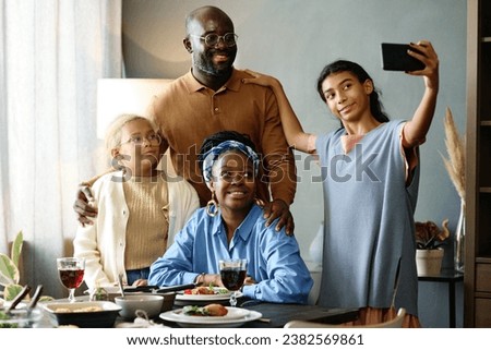 Pretty girl with smartphone taking picture of her parents and sister