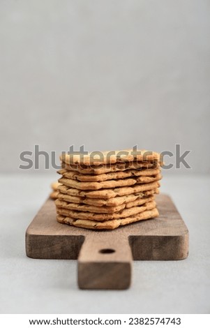 Multigrain crunchy cookies with flax and sesame seeds on wooden cutting board on light background 