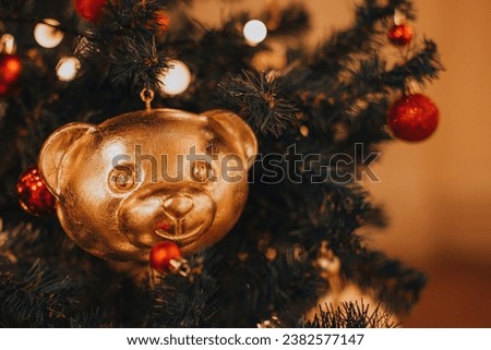 Creative Christmas decor. Golden festive Christmas toy figurine of teddy bear head hanging on Christmas tree. Winter holiday and New Year details