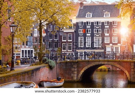 Amsterdam, Netherlands. Bridge view of autumn Dutch city. Famous channel Amstel river. Evening cityscape. Colorful sunset scene famous travel destination in Europe. Romantic traveling place.