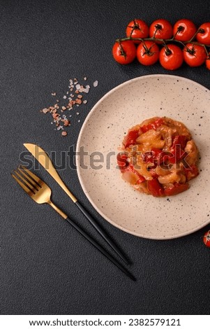 Delicious fresh salad with slices of grilled chicken, pineapple, sweet pepper, nuts and sauce on a ceramic plate on a dark concrete background
