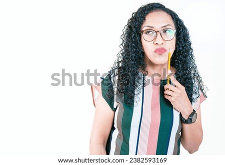 Thoughtful young woman in glasses holding a pencil. Afro girl thinking holding pencil on chin