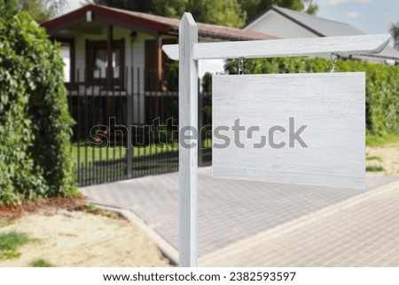 Empty white wooden sign near beautiful house outdoors