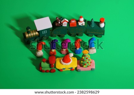 A toy train and figures of dwarfs on a green background. Christmas decorations.