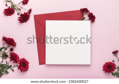 Red envelope and blank card, red chrysanthemums on a pink background. Greeting card, mockup.