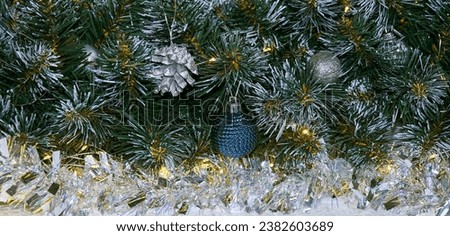 Christmas background with Christmas tree branches and silver tinsel in the light of golden garland.  Christmas holiday picture with copyspace