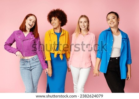 Group attractive smiling multiethnic women wearing stylish colorful outfit  looking at camera isolated on pink  background. Portrait happy fashion models, friends posing for pictures. Diversity