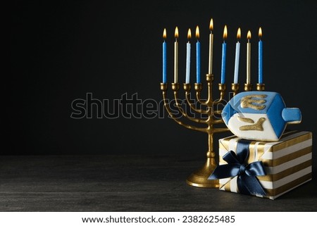Hanukkiah, gingerbread and gift box on black background, space for text