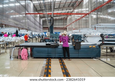 Industrial cloth cutting machine and fabric cutting area in garment factory in industrial zone in Ho Chi Minh City, Vietnam, with modern machinery and technology systems.