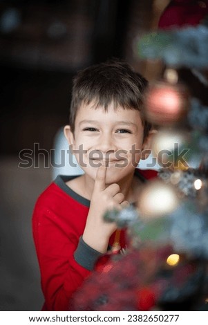 Cute adorable boy reading a book in front of the christmas tree, christmas time
