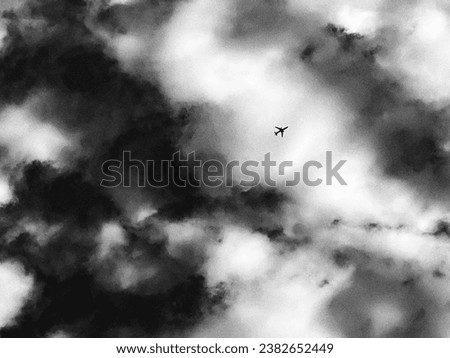 Monochromatic picture of an airplane flying in dramatic sky with scattered clouds