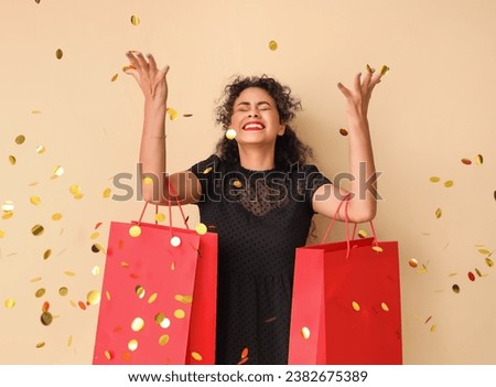 Beautiful African-American woman with shopping bags and confetti on beige background. Black Friday sale