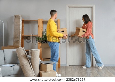 Happy young couple with boxes near door in room on moving day Royalty-Free Stock Photo #2382679259