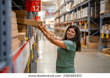 Woman customer looking up and pulling product on shelf while shopping in storage of shop. High quality photo