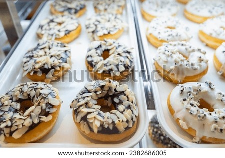 Assorted fresh donuts on display racks at the donut shop.Display of delicious pastries with assorted glazed donuts in shop.Various donuts on shelf in Bakery.Colorful flavor donuts with coating,topping Royalty-Free Stock Photo #2382686005