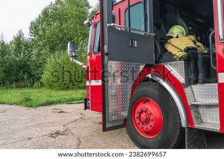 The open door of the fire truck cabin where the firefighters are located. The firefighter's protective clothing is in the cabin of the fire truck. The 911 rescue service. Equipment for saving people. Royalty-Free Stock Photo #2382699657