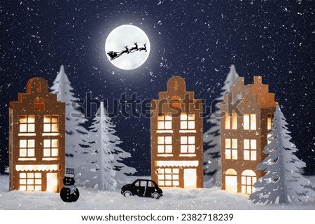 Winter village made of paper. Paper winter city night landscape with Santa Clause sleigh over full moon. Creative Christmas composition with paper house. Christmas winter background.