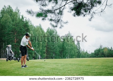 Male golfer plays golf on golf course. Golfer hitting golf ball