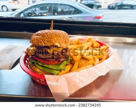 Burger and fries in red tray with view of street in background. Fast food at a restaurant in California. Food on a metal counter with receipt on left side.