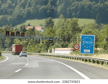 large road sign with the text ITALIA and yellow European stars near the Italian border in the mountains