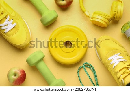 Barbell plate, shoes, apples, headphones and dumbbells on yellow background Royalty-Free Stock Photo #2382736791
