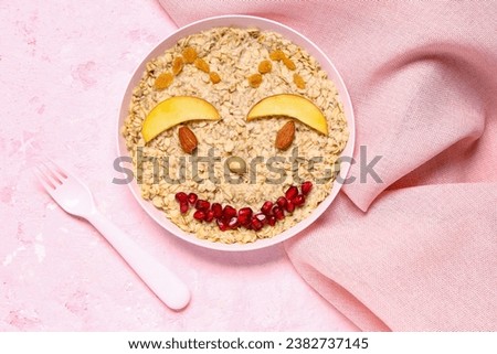 Plate of tasty oatmeal for children, napkin and fork on color background