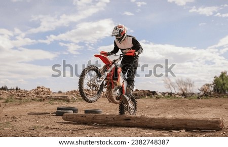 Man on dirt bike jumping a log in the desert