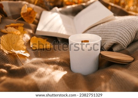 Candle and open book in nature, autumn concept.