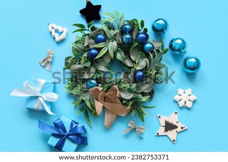 Christmas mistletoe wreath with balls and gift boxes on blue background