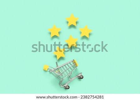 Shopping cart with five stars rating on turquoise background. Customer experience concept Royalty-Free Stock Photo #2382754281