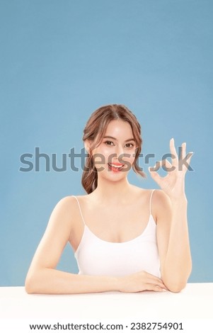 Young Asian beauty woman pull back hair with Koreans makeup style on face and perfect clean skin show OK sign on isolated blue background.