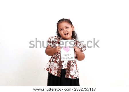 Adorable asian little girl in batik showing happy fathers day greeting card. Isolated on white background