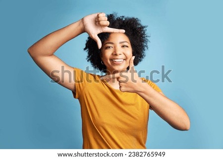 Portrait, frame and woman with a smile, focus and confident girl against a blue studio background. Face, female person or model with hand gesture, framing and shape with profile picture and happiness